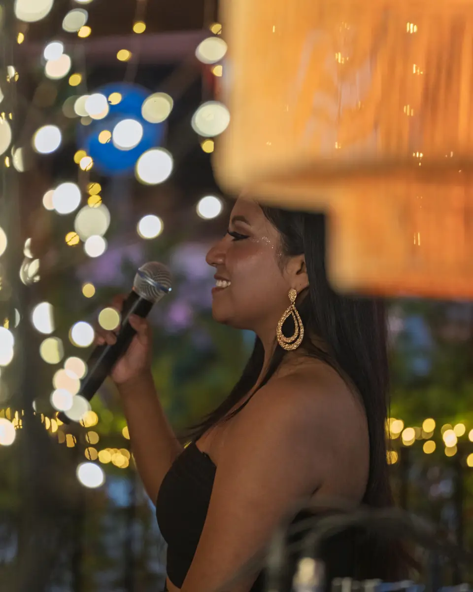 A singer performing with the terrace lights out of focus behind her