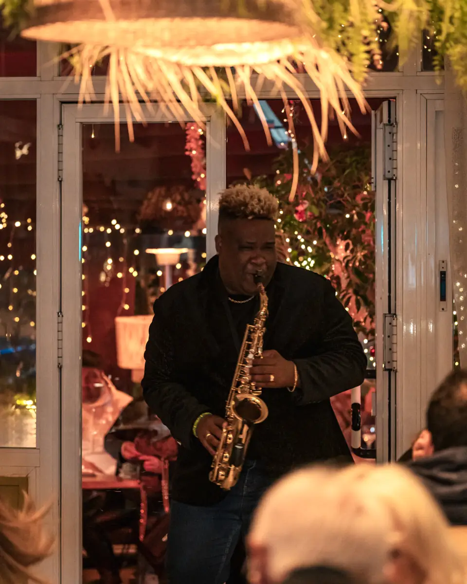 A saxophonist playing across a full room at Pachamama